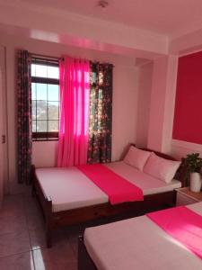 a bedroom with two beds and pink curtains at EMILIEZ PLACE in Baguio