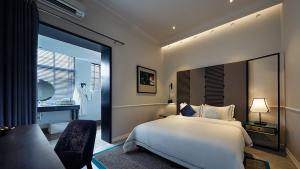 a bedroom with a white bed and a bathroom at The Edison George Town in George Town