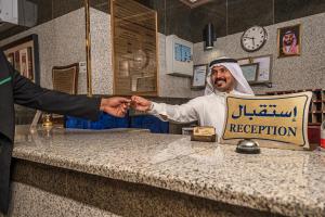 a man shaking another mans hand over a counter at فندق غالية احد in Al Madinah