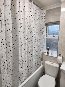 a bathroom with a toilet and a shower curtain at Home away from Home in Woolwich