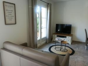 ein Wohnzimmer mit einem Sofa und einem TV in der Unterkunft Le Mazet d'Olivia, escapade romantique en Provence in Châteauneuf-de-Gadagne