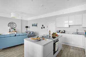 a kitchen and living room with white cabinets and a blue couch at THE ANGEL 1 BEST VIEWS IN DARTMOUTH in Dartmouth