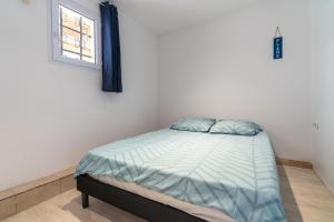 een klein bed in een kamer met een raam bij Maison de pecheur la rose des vents in Valras-Plage