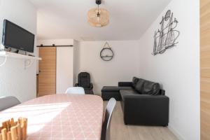 een kamer met een bed, een bank en een tv bij Maison de pecheur la rose des vents in Valras-Plage