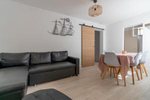 een woonkamer met een zwarte bank en een tafel bij Maison de pecheur la rose des vents in Valras-Plage