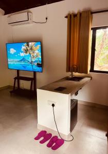 ein Wohnzimmer mit einem TV und einem Tisch mit Hausschuhen in der Unterkunft Bissa Villa in Habarana