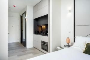 a bedroom with a white bed and a kitchen at Spacious Studio Apartments at Dandi on The Hill in Harrow