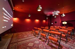 an auditorium with red walls and chairs and a screen at Spacious Studio Apartments at Dandi on The Hill in Harrow