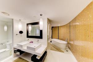 a bathroom with two sinks and a tub and a toilet at Cinnamon Grand Colombo in Colombo