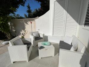 patio z białymi wiklinowymi krzesłami i stołem w obiekcie Casa Flavia w mieście Torre Chianca