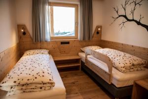 2 camas en una habitación pequeña con ventana en Kieserhof Apartment Wald, en Terento