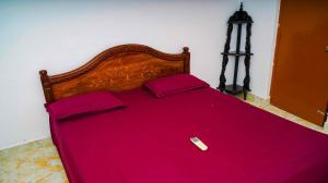 łóżko z czerwoną pościelą i pilotem w obiekcie Bacardi House w mieście Ćennaj