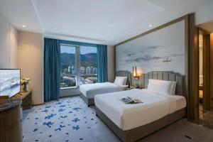 Habitación de hotel con 2 camas y ventana grande. en Kyushu Joycheng Hotel, en Shenzhen