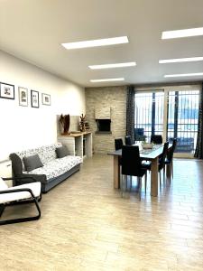a living room with a couch and a table and chairs at Le Mandorle Apartment in Belpasso