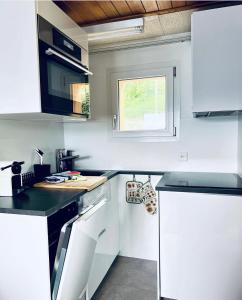 una pequeña cocina con armarios blancos y una ventana en Chalet Wiesehockli - CharmingStay, en Flumserberg