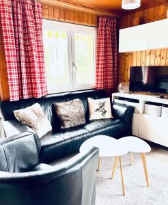 un soggiorno con divano in pelle nera di Chalet Wiesehockli - CharmingStay a Flumserberg