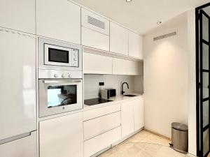 eine weiße Küche mit weißen Schränken und einer Mikrowelle in der Unterkunft Suite Deluxe Gondomar in Córdoba