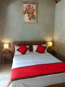 a bedroom with a bed with two red pillows at Nirmala Guest House in Ubud