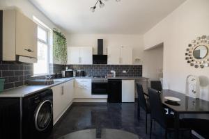 a kitchen with a washer and a table with chairs at Chelmsford House By Horizon Stays in Darlington