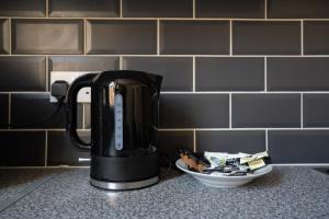 a coffee pot on a counter next to a plate of food at Chelmsford House By Horizon Stays in Darlington