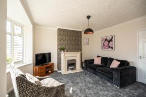 sala de estar con sofá negro y chimenea en Brinkburn House By Horizon Stays, en Stockton-on-Tees