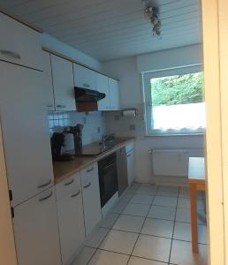 eine kleine Küche mit weißen Schränken und einem Fenster in der Unterkunft FeWo Hirschblick in Brilon