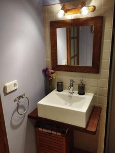 een badkamer met een witte wastafel en een spiegel bij Llar compartida El Tupí in Sant Juliá de Vilatorta