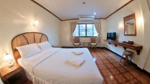 1 dormitorio con 1 cama blanca grande y escritorio en Roongruang Hotel, en Chiang Mai