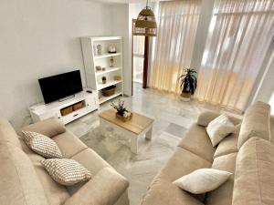 Apartamento Arellano في كارمونا: غرفة معيشة مع أريكة وتلفزيون