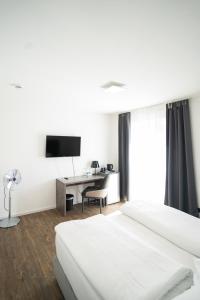 a bedroom with a bed and a desk with a television at AP Hotel Mannheim Viernheim in Viernheim
