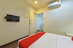 1 dormitorio con 1 cama y TV en la pared en OYO 90853 New Soho Hotel, en Cuevas de Batu