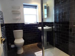a black tiled bathroom with a toilet and a sink at The Brighton Parlour with Hot Tub in Brighton & Hove +20 photos