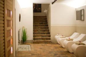 a hallway with a row of white chairs and stairs at Hotel Palazzo San Niccolò & Spa in Radda in Chianti