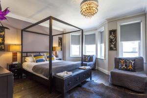 a bedroom with a canopy bed and a chair at Bournemouth Beach Boutique with Hot Tub in Bournemouth