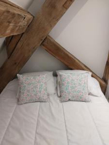 een bed met witte lakens en kussens op een zolder bij Appartement, Langres in Langres