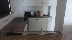 a small kitchen with a sink and a microwave at Quattro Beachfront Sea View Ap 53 in Larnaka