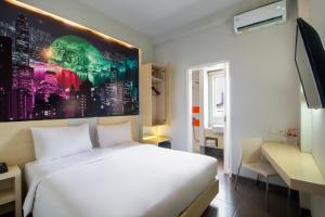 Un dormitorio con una cama blanca y una pintura en la pared en Cleo Business Hotel Walikota Mustajab City Center, en Surabaya