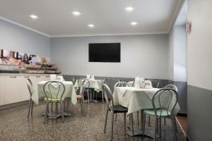 uma sala de jantar com mesas e cadeiras e uma televisão em Hotel Assarotti em Gênova
