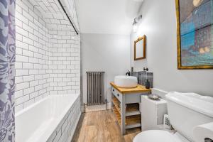 a bathroom with a white tub and a sink at The House of Black & White in Great Torrington