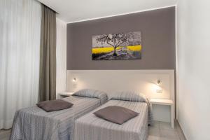 two beds in a hotel room with yellow flowers at Hotel Assarotti in Genoa