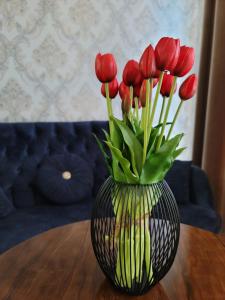 IZZA PALACE Hotel في طشقند: مزهرية مع زهور الأقحوان الحمراء فيها على طاولة