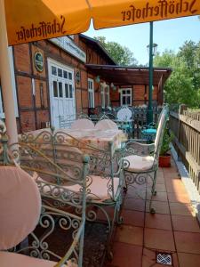 um pátio exterior com mesas, cadeiras e um guarda-sol em Hotel Schützenhaus Lenzen em Lenzen