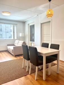 uma sala de jantar com uma mesa e cadeiras e um sofá em Guest apartment with view and terrace, Vuosaari, Helsinki, self check-in em Helsinque