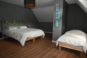 um quarto com 2 camas com lençóis brancos e pisos de madeira em La Villa du Papetier em Boussières