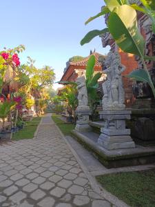 a street with two stone statues in front of a building at Nirmala Guest House in Ubud +17 photos
