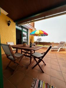 a wooden table with chairs and an umbrella on a patio at CASA COREA IV in Puntagorda