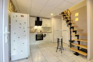 a kitchen with a white refrigerator and a staircase at Aux volets bleus in Badonviller