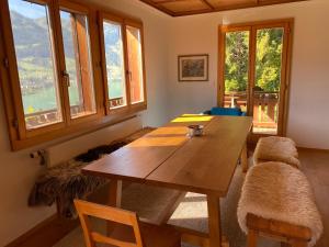een woonkamer met een houten tafel en een aantal ramen bij Chalet Seeblick in Sarnen