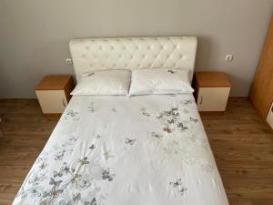 Una cama con una colcha blanca con flores. en Varna City Apartment, en Varna