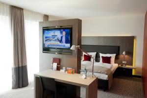 Habitación de hotel con cama y TV en la pared en bigBOX ALLGAEU Hotel, en Kempten